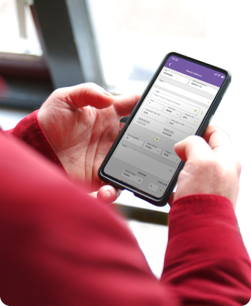 Osoba trzyma smartfon, na ekranie którego widać interfejs aplikacji do zabezpieczenia domu.